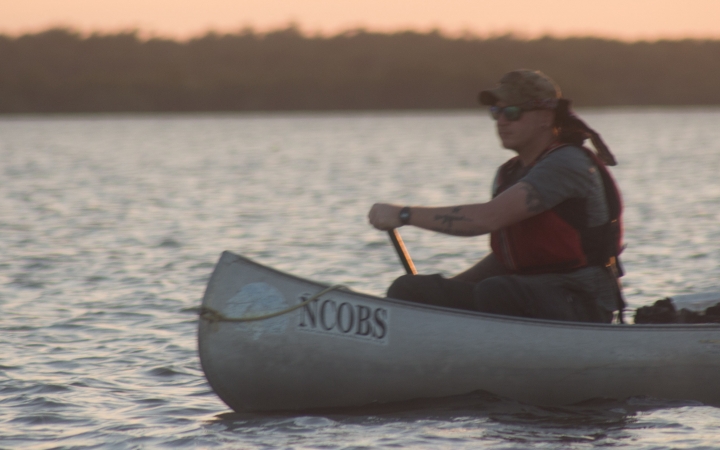 a person paddles a canoe on an outward bound veterans expedition